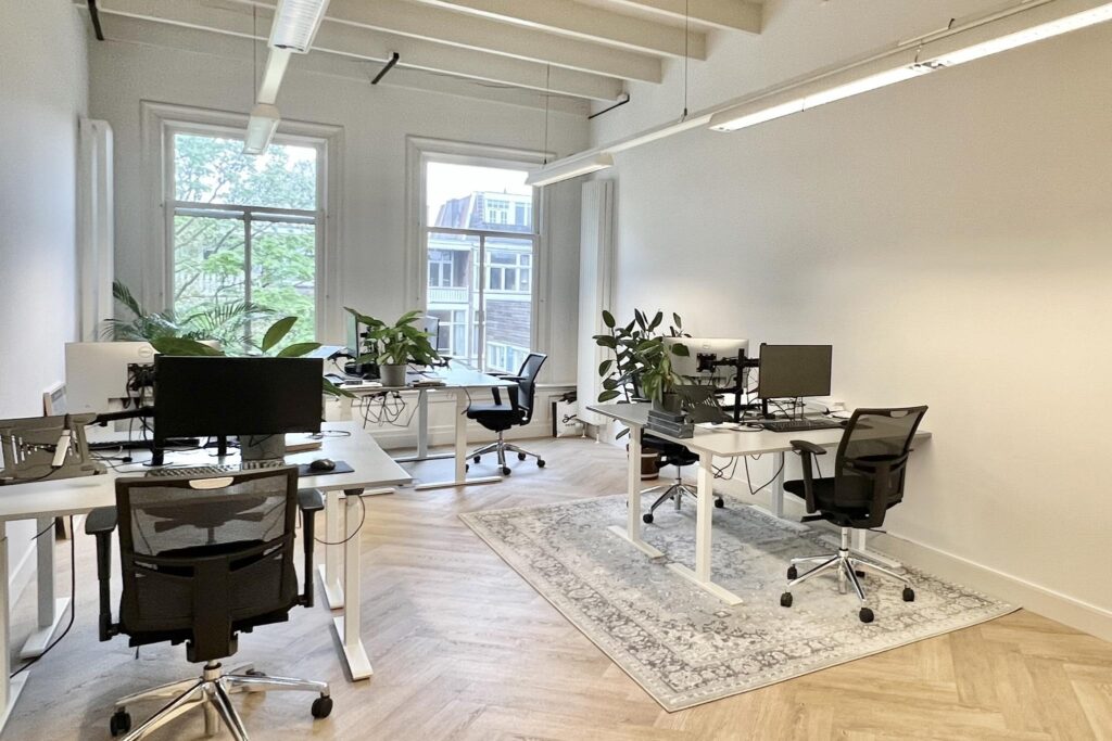 Licht en modern kantoor aan de Paulus Potterstraat met bureaus, bureaustoelen, computers en groene planten.